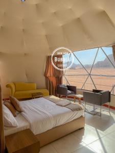 瓦迪拉姆Wadi rum Bubble luxury camp的一间卧室配有床、椅子和窗户
