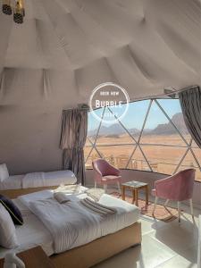 瓦迪拉姆Wadi rum Bubble luxury camp的一间卧室配有一张床、两把椅子和一个窗户