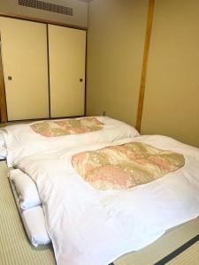 箱根吉池日式旅馆的配有白色床单的客房内的两张床