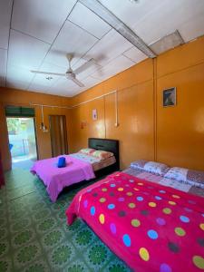 瓜拉勿述B'first Chalet Perhentian Island的配有粉红色和紫色床单的客房内的两张床