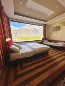 锡卡都Skardu Luxus Hotel的一间卧室设有两张床和大窗户