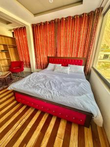 锡卡都Skardu Luxus Hotel的窗户客房内的一张红色的床