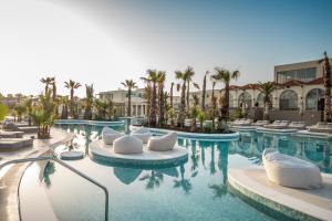 赫索尼索斯Europa Beach Hotel & Spa的酒店游泳池设有白色椅子和棕榈树