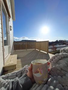 于尔斯泰因维克Charming house in Ulsteinvik with free parking的把咖啡杯放在阳台上的手