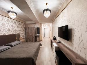 奇姆肯特Stela Hotel的一间卧室配有一张床和一台平面电视