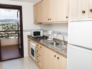 卡尔佩Apartamentos Coral Beach Unitursa的厨房配有水槽和炉灶 顶部烤箱