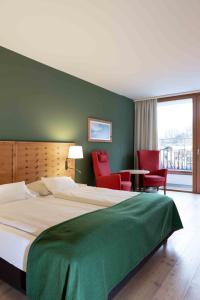 巴特奥塞俄泽佐格约翰SPA酒店的一间卧室配有一张大床和红色椅子