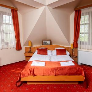 锡盖特圣米克洛什Gastland M0 Hotel & Conference Center的一间卧室配有一张铺有红地毯的大床