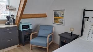 韦斯特卡佩勒studio B&B Zeeuws licht的一间卧室配有一张床、一把椅子和电视。