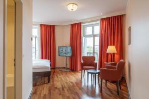 巴塞尔巴塞尔施维瑟酒店的酒店客房,配有床和红色窗帘