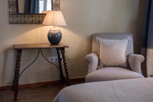 贝赫尔-德拉弗龙特拉卡利法之家酒店的椅子旁边的桌子上的一盏灯