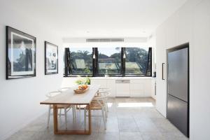 悉尼The Treehouse Penthouse的白色的厨房配有木桌和椅子