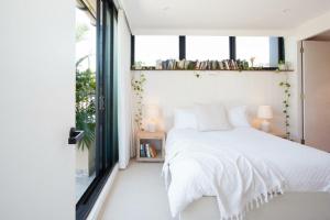 悉尼The Treehouse Penthouse的卧室配有白色的床和窗户。