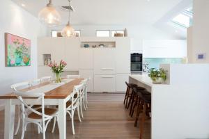 悉尼The Cali Beach house Bronte的白色的厨房配有木桌和椅子
