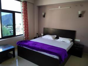 PithorāgarhHotel-78的一间卧室配有一张带紫色床单的大床和窗户。