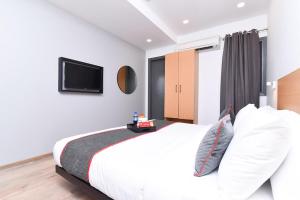 新德里Hotel Rudra的卧室配有白色的床和平面电视。