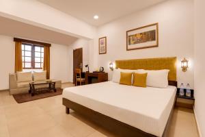 达博利Lemon Tree Hotel, Dapoli的卧室配有一张白色大床和一把椅子