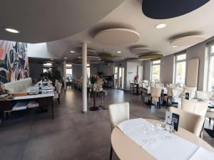 沙勒罗瓦Aero44 Hotel Charleroi Airport的餐厅设有白色的桌椅和窗户。