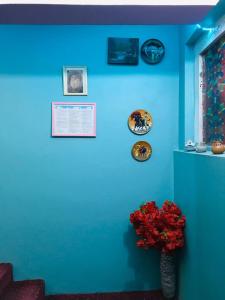 坎大哈Millat Hotel & Noor Jahan Hotel Kandahar的蓝色的墙壁,上面有红花花瓶