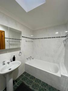 悉尼Comfortable 3 Bedroom House Pyrmont的白色的浴室设有水槽和浴缸。