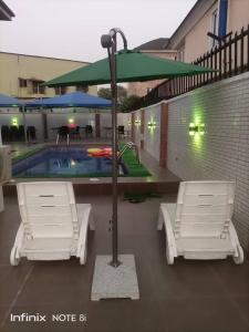 伊凯贾White Gold Hotel的游泳池前的两把椅子和一把遮阳伞