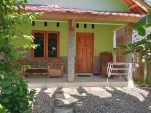 瑟克通Pelangi Homestay Bungalow Gili gede的一座带红色门的小绿色房子