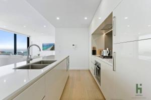 悉尼St Leonards 2B2B Apt with Skyview的白色的厨房配有白色的柜台和水槽