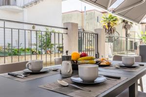 利多迪耶索罗GIGI HOUSE [appartamento PIAZZA MAZZINI] 300m dal mare的阳台上的桌子上放有盘子、杯子和水果