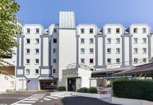 鲁昂B&B HOTEL Rouen Centre Rive Droite的前面有一条街道的白色大建筑