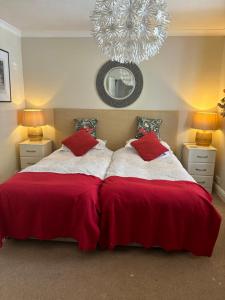 韦德布里奇Gwynarth Guest House的一间卧室配有一张带红色床单和吊灯的床。