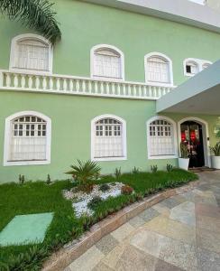 福塔莱萨科克尔酒店的绿色的房子,设有白色的窗户和庭院