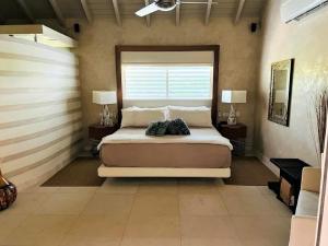 Jolly HarbourCasa frente al mar en Antigua的一间卧室配有一张大床、两张桌子和一扇窗户
