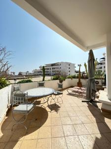 阿加迪尔Fabulous Apartment in Marina Agadir的庭院配有桌椅和遮阳伞。