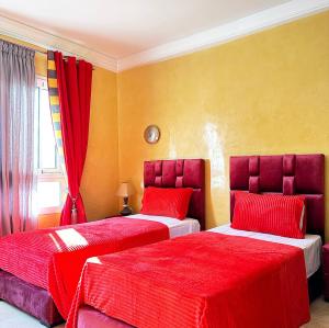 阿加迪尔Fabulous Apartment in Marina Agadir的一间卧室配有两张红色床罩