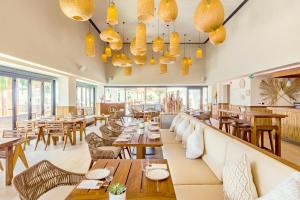 拉斯阿尔卡麦Mövenpick Resort Al Marjan Island的餐厅设有木桌、椅子和窗户。