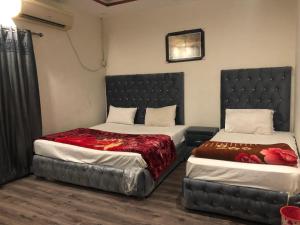 拉合尔Defence-Mark-Hotel的一间卧室配有两张床和床头板