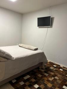拉热斯Norte Hospedagem的卧室配有一张床,墙上配有电视。