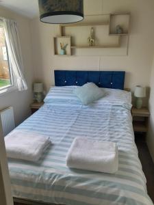 塔特舍尔Luxury Hot Tub Caravan Tattershall的一张蓝色的床,上面有两条白色的毛巾