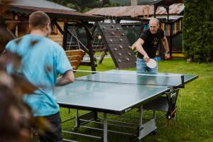 弗塞廷Apartmány Velké Karlovice的两个男人在乒乓球桌玩乒乓球
