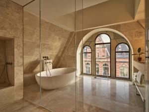 阿姆斯特丹Conservatorium Hotel的带浴缸和玻璃淋浴间的浴室。