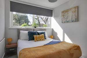切姆Niche Sunrise Townhouse的卧室配有带枕头的床铺和窗户。