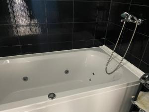 沙布拉Ferienhaus in Strandnähe的浴室铺有黑色瓷砖,配有白色浴缸。