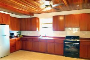 库尔克岛VeLento Partial Ocean View #8的厨房配有木制橱柜和白色冰箱。