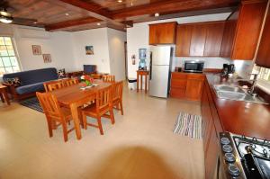 库尔克岛VeLento Partial Ocean View #8的厨房以及带木桌和椅子的客厅。