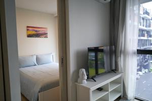 邦涛海滩Modern 2-bedroom Apartments. Skypark Laguna (Bang Tao)的一间卧室设有一张床、一台电视和一个窗口。