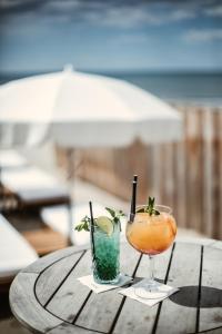 拉格朗德默特Hôtel La Plage 5 étoiles La Grande Motte的木桌边的2杯鸡尾酒