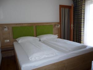 湖滨福煦Haus Lungau的一张带白色枕头和绿色床头板的大床