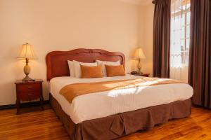 圣何塞Casa Conde Hotel & Apartamentos的一间卧室配有一张大床和两盏灯。