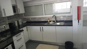 里斯本Quarto Aeroporto的厨房配有白色橱柜、水槽和窗户。
