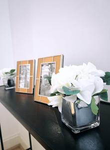 伦敦LUX Flat Marylebone Oxford Street的一张带白色花朵的花瓶,桌子上摆放着照片